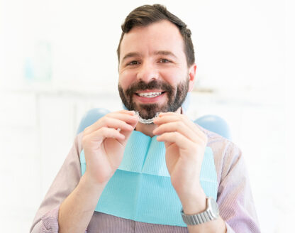 Guy is holding Invisalign in his hands and smiling